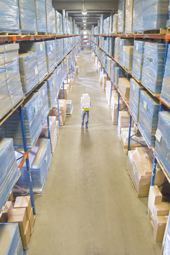 Warehouse worker carrying boxes in aisle